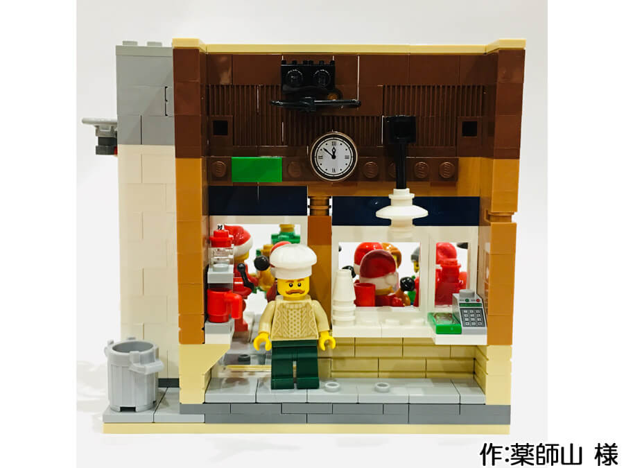 サンタに扮した音楽隊が街角の広場に集まるクリスマス作品。カフェにはエスプレッソマシーンが置かれています。